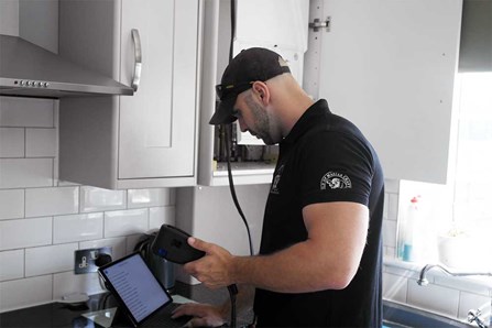 Plumber in kitchen servicing and repairing boiler. 