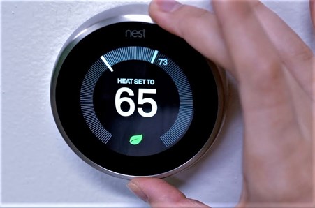 A persons fingers setting a nest smart thermostat